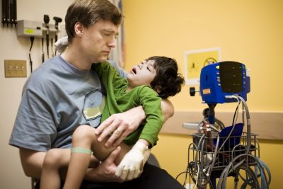 Father holding his disabled son in a hospital