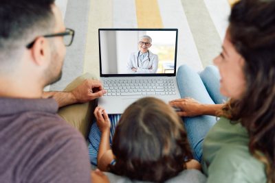 Back view of family making video call with their doctor while staying at home